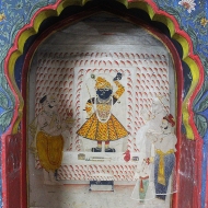 The men in the royal family worshipping Krishna in an alcove painting.